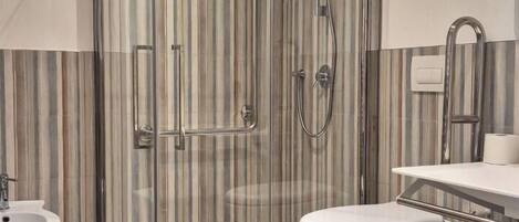 A modern bathroom with a glass-enclosed shower, a bidet, a toilet, and a vanity with a mirror.