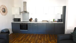 A modern kitchen with dark cabinets, a microwave, a kettle, and a toaster.