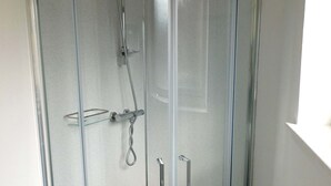 Una doccia vetrata con soffione a mano e rubinetto a leva.