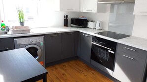 Una cucina moderna con mobili grigi, lavastoviglie integrata, forno a microonde, tostapane e piano cottura.