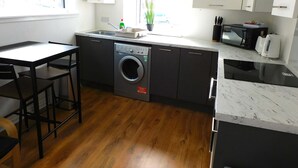 Cucina compatta con lavatrice integrata, forno a microonde e tostapane.