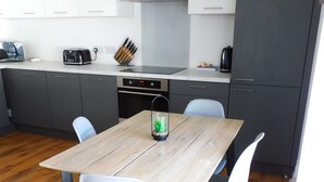 A modern kitchen with grey cabinets, a wooden dining table, and two chairs.