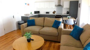 A modern living room with a beige sofa, a round wooden coffee table, and a small potted plant.