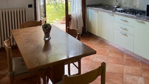 Eine Küche mit Essbereich, ausgestattet mit einem Holztisch, Stühlen, einem Heizkörper und Blick ins Grüne.
