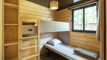 Een houten kamer met een stapelbed, een plankenwand en een raam met uitzicht op bomen.