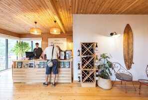 A wooden interior with a reception desk, a wine rack, and a surfboard on the wall. - Huttopia Arcachon  (Arcachon)