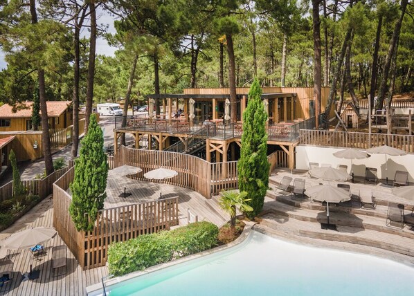A resort with a pool, outdoor seating, and a wooden deck. - Huttopia Arcachon  (Arcachon)