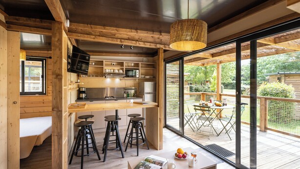 Eine moderne Küche mit Holzelementen, ein Essbereich mit Tisch und Stühlen und eine große Glasschiebetür, die auf eine Außenpatio führt.