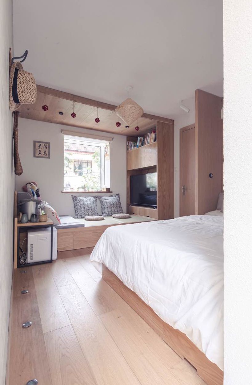 A bedroom with a bed, a TV, a desk, and a window.