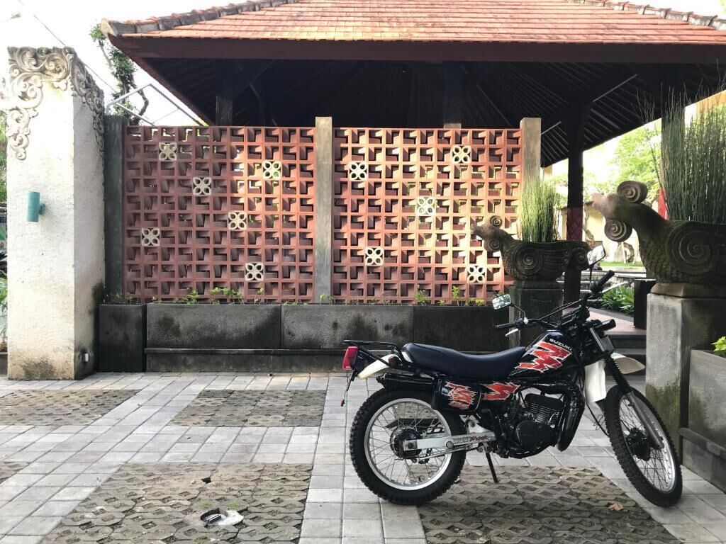 Una motocicleta estacionada frente a un edificio con piso de baldosas y una valla decorativa.