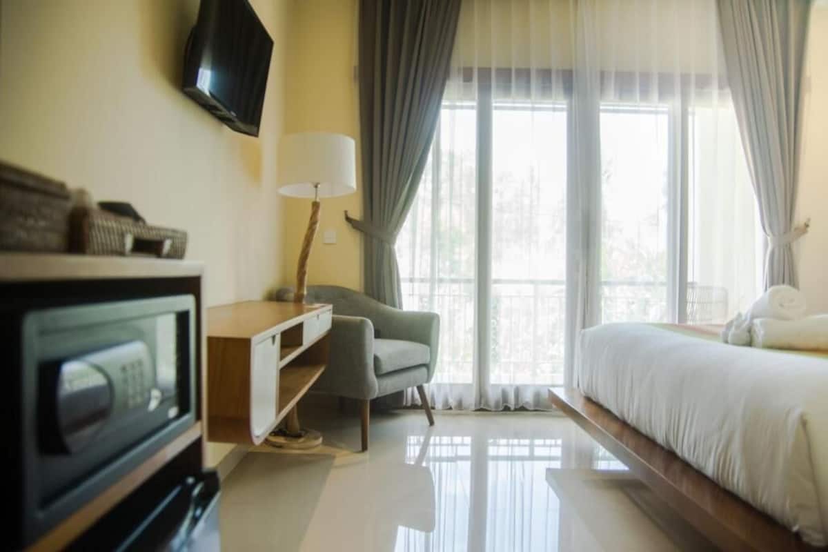 A hotel room with a bed, a desk, a chair, a television, and a window with curtains.