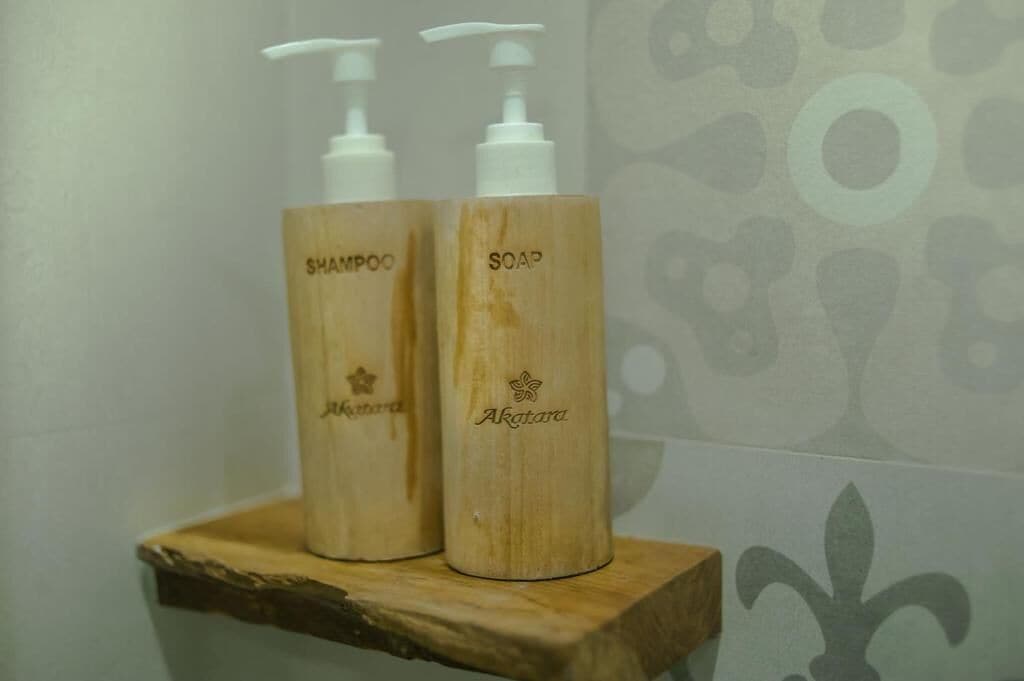 Two wooden bottles of shampoo and soap on a shelf.