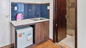 Une cuisine de taille réduite, équipée d’un évier, d’un réfrigérateur et d’un meuble en bois.