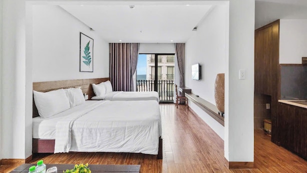 Une chambre d’hôtel avec deux lits, une télévision, un balcon et un plancher en bois.