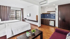 Une chambre d’hôtel avec deux lits, une petite kitchenette, une salle de bain et un coin salon.