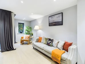 Un salon avec un canapé, un fauteuil, une lampe et une fenêtre.