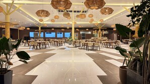 A spacious hotel lobby with a checkered floor, multiple dining tables, and hanging spherical light fixtures. - Hotel Prince Garden Daman (Daman)