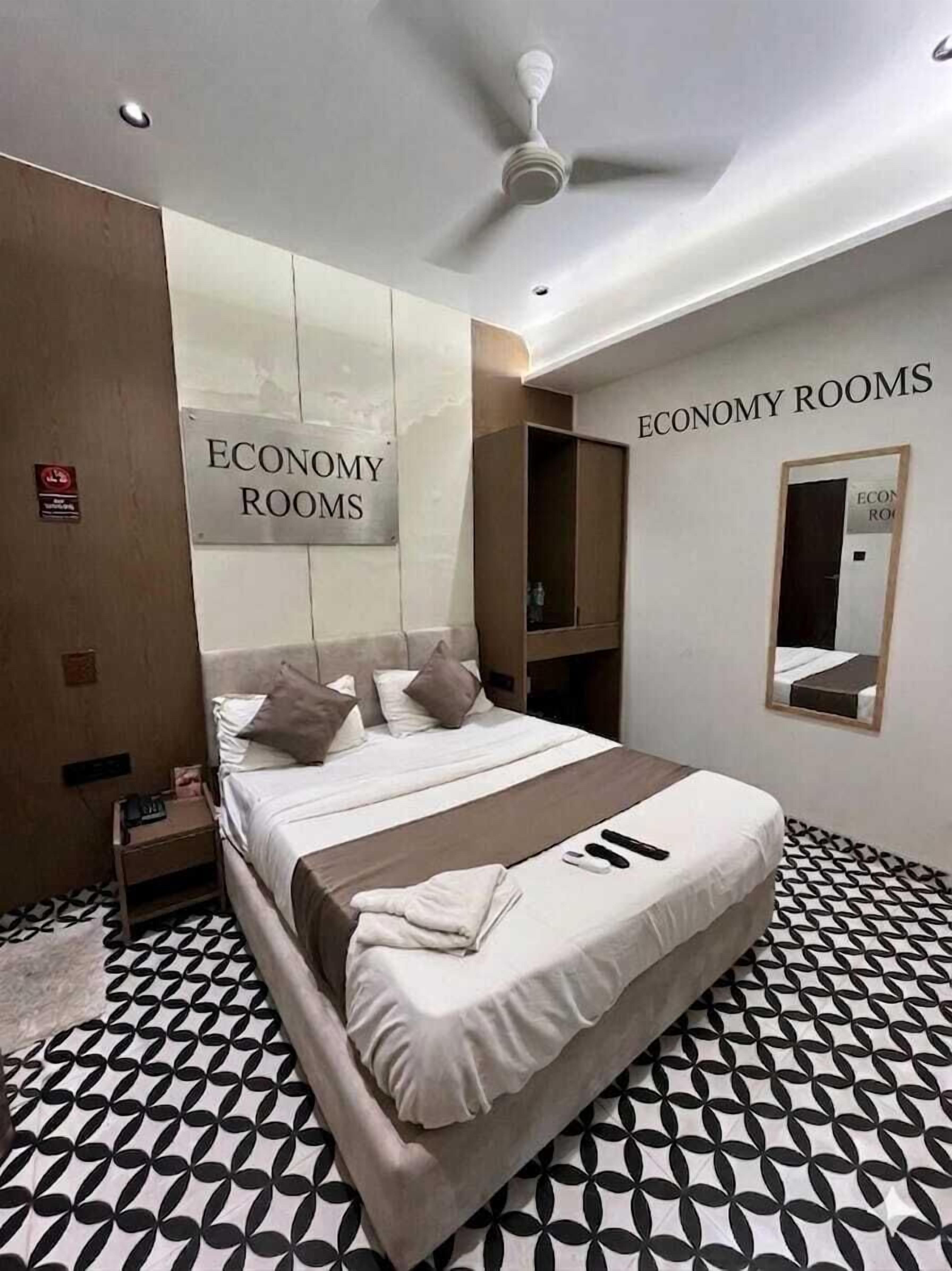 Una habitación de hotel con cama, ventilador de techo y un cartel que indica 'ECONOMY ROOMS'.