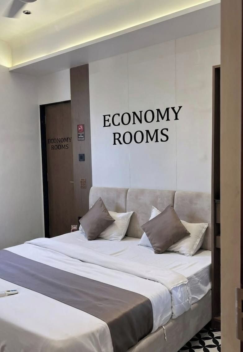 A bedroom with a bed, pillows, and a wall sign that reads 'ECONOMY ROOMS.'