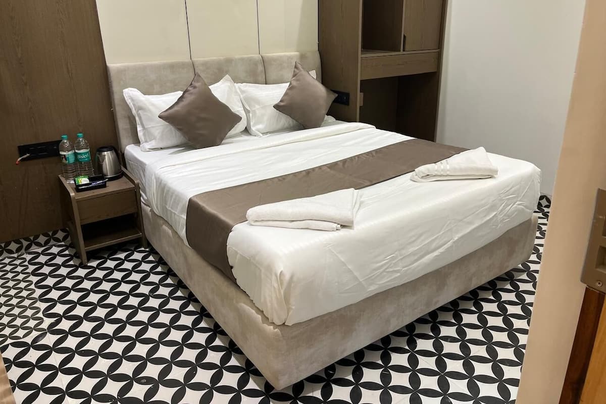 Une chambre d’hôtel avec un lit, une table de chevet et un sol à motifs.