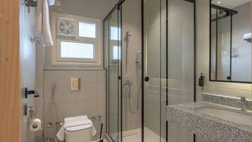 Une salle de bain moderne avec une douche à parois de verre, des toilettes blanches et un lavabo sur un plan de travail en granit.