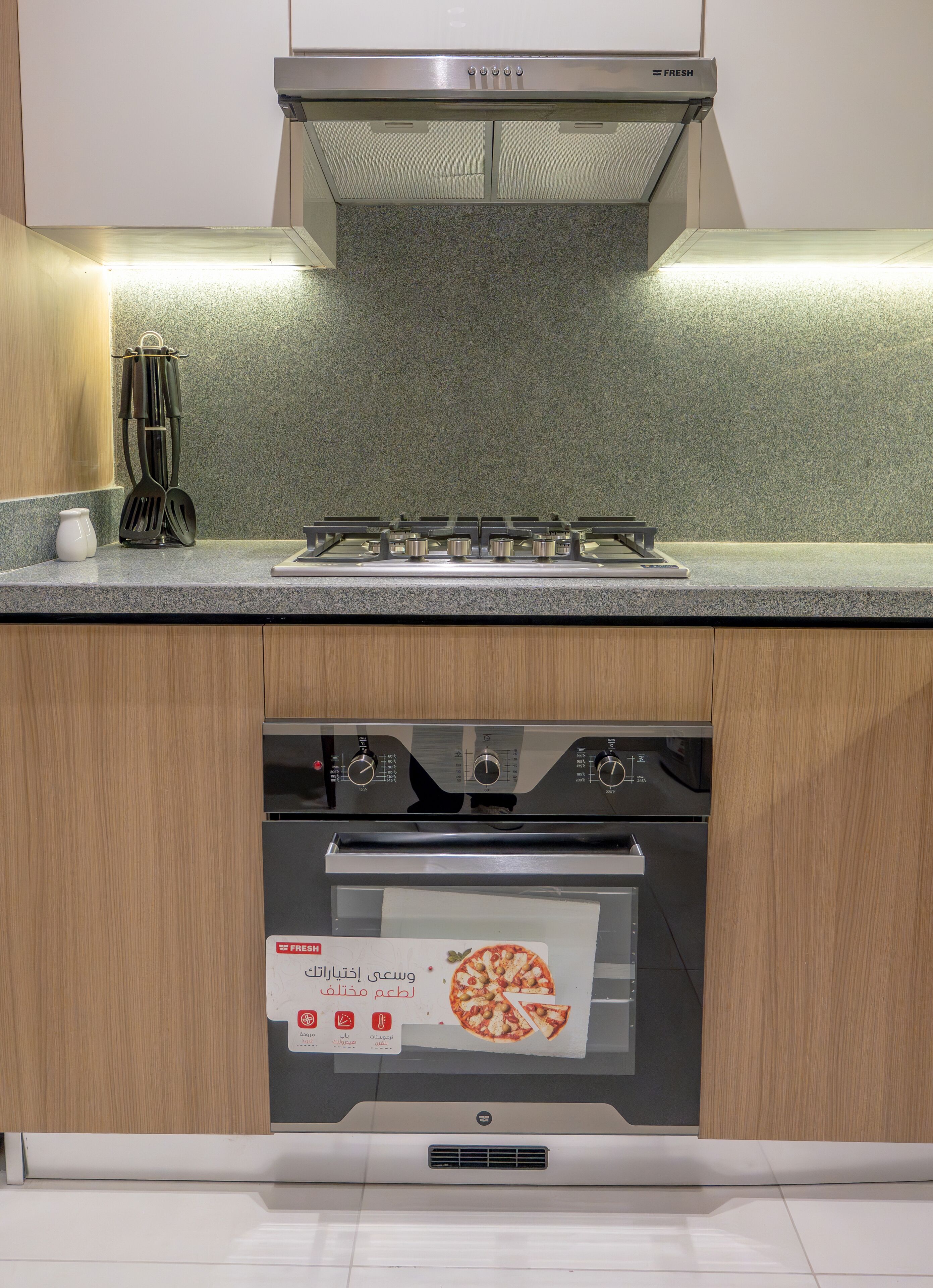 A kitchen with a stainless steel range hood, a built-in oven, and a microwave.
