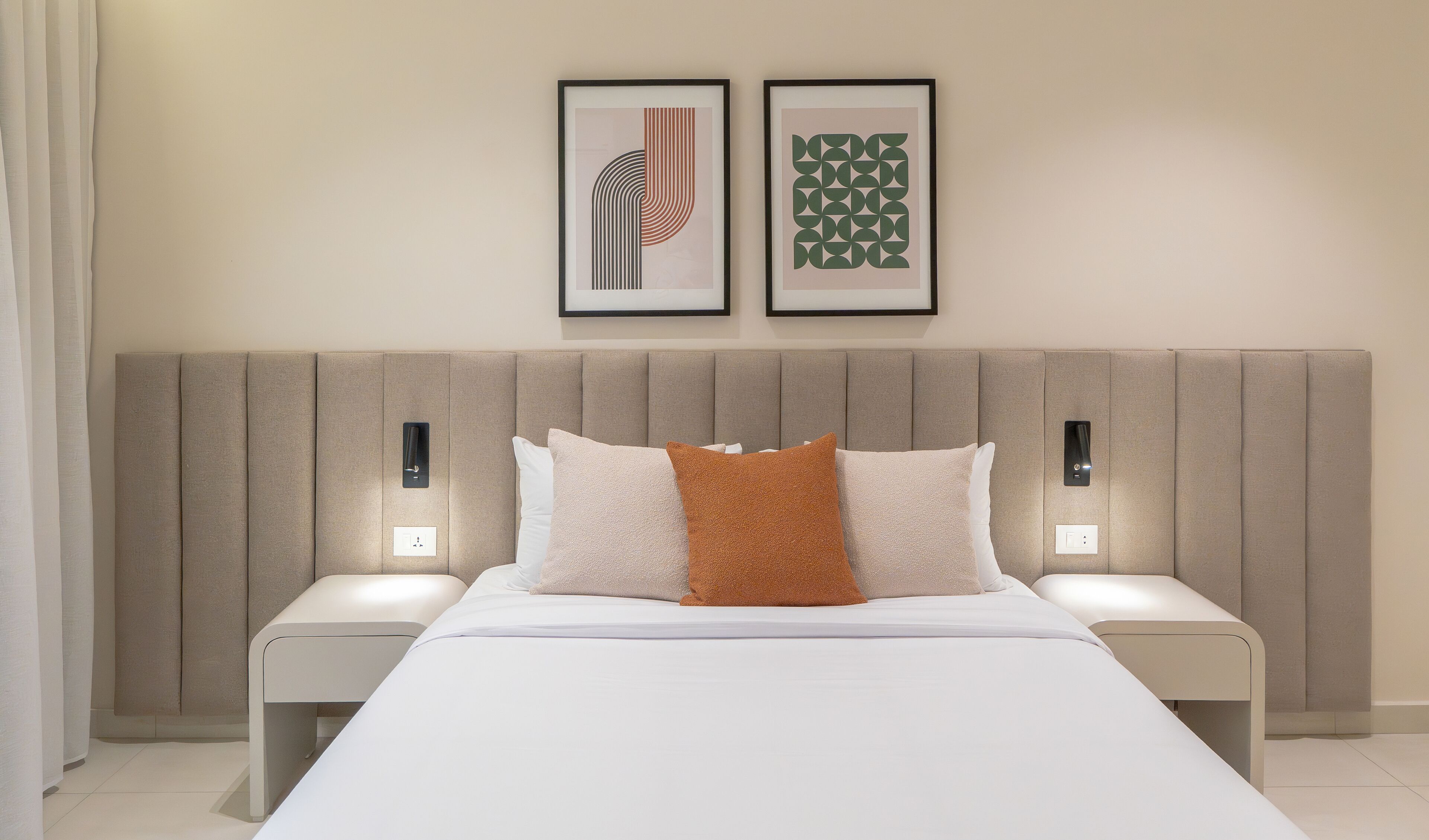 Una habitación de hotel moderna con una cama grande, dos mesitas de noche y dos lámparas fijadas a la pared.