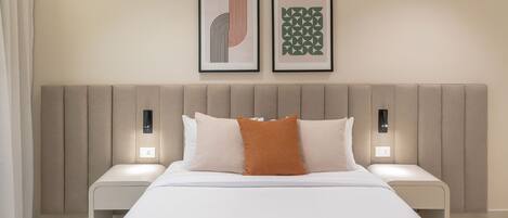 A modern hotel room with a large bed, two bedside tables, and two wall-mounted light fixtures.