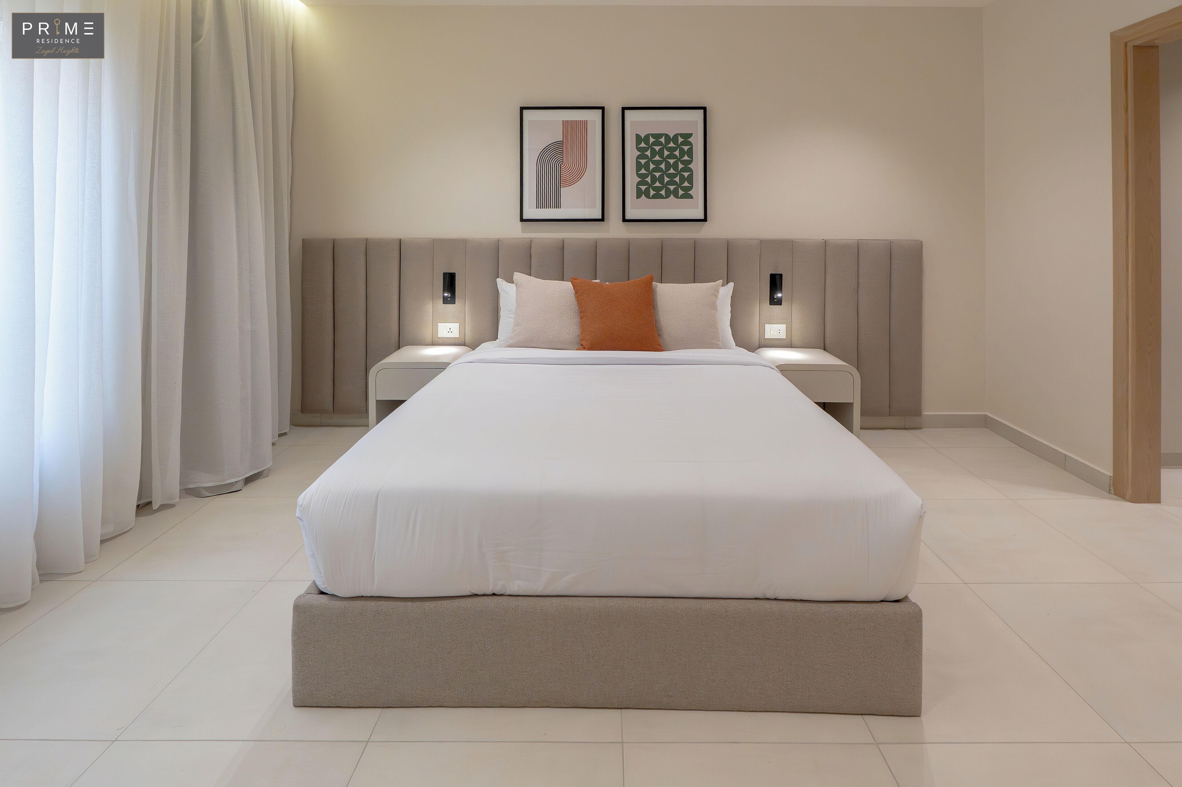 Una habitación de hotel moderna con una cama grande, dos mesitas de noche y un cabecero con iluminación integrada.