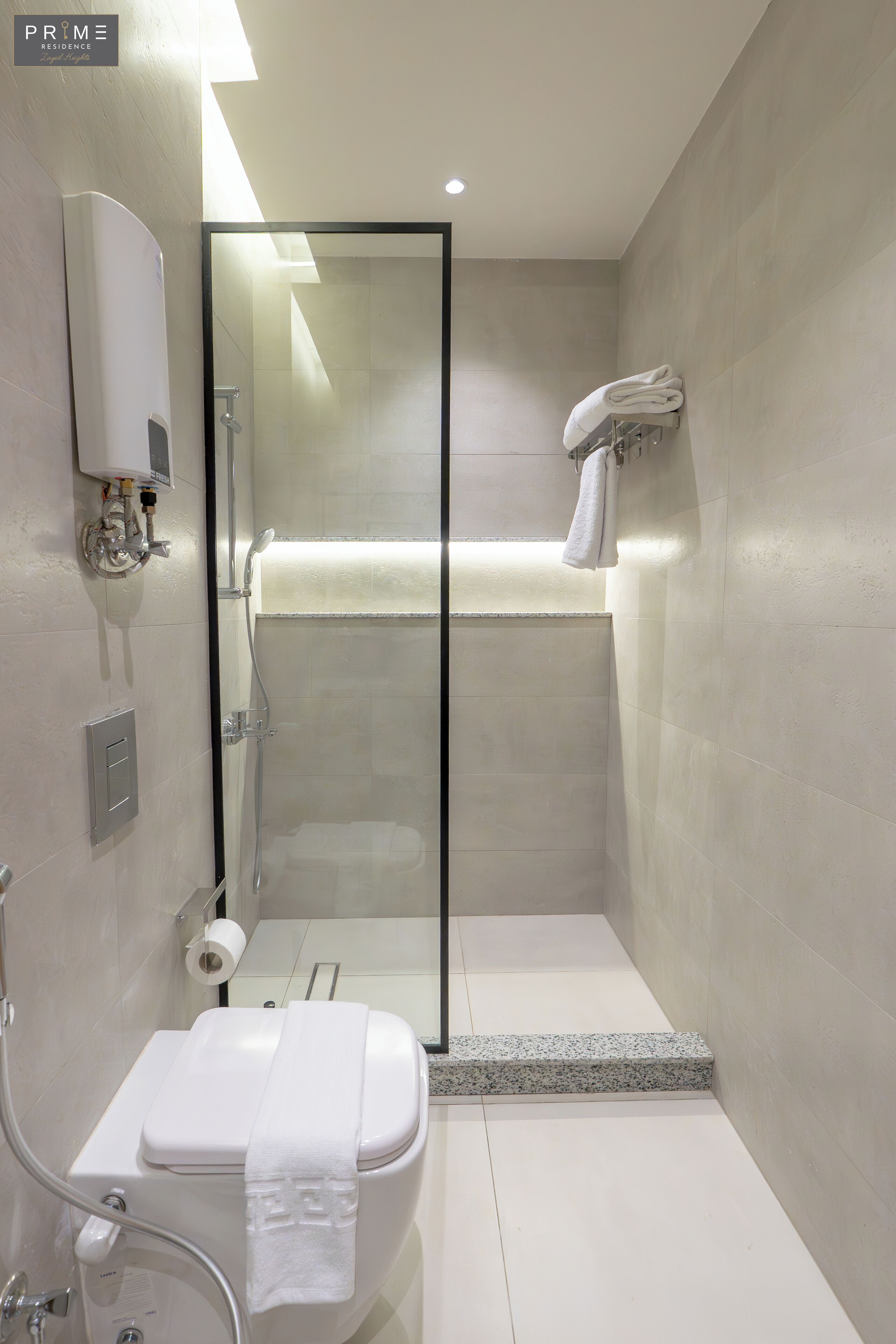 Une salle de bain moderne avec une douche à parois de verre, des toilettes et un porte-serviettes.