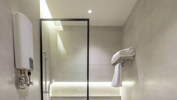 Une salle de bain moderne avec une douche à parois de verre, des toilettes et un porte-serviettes.