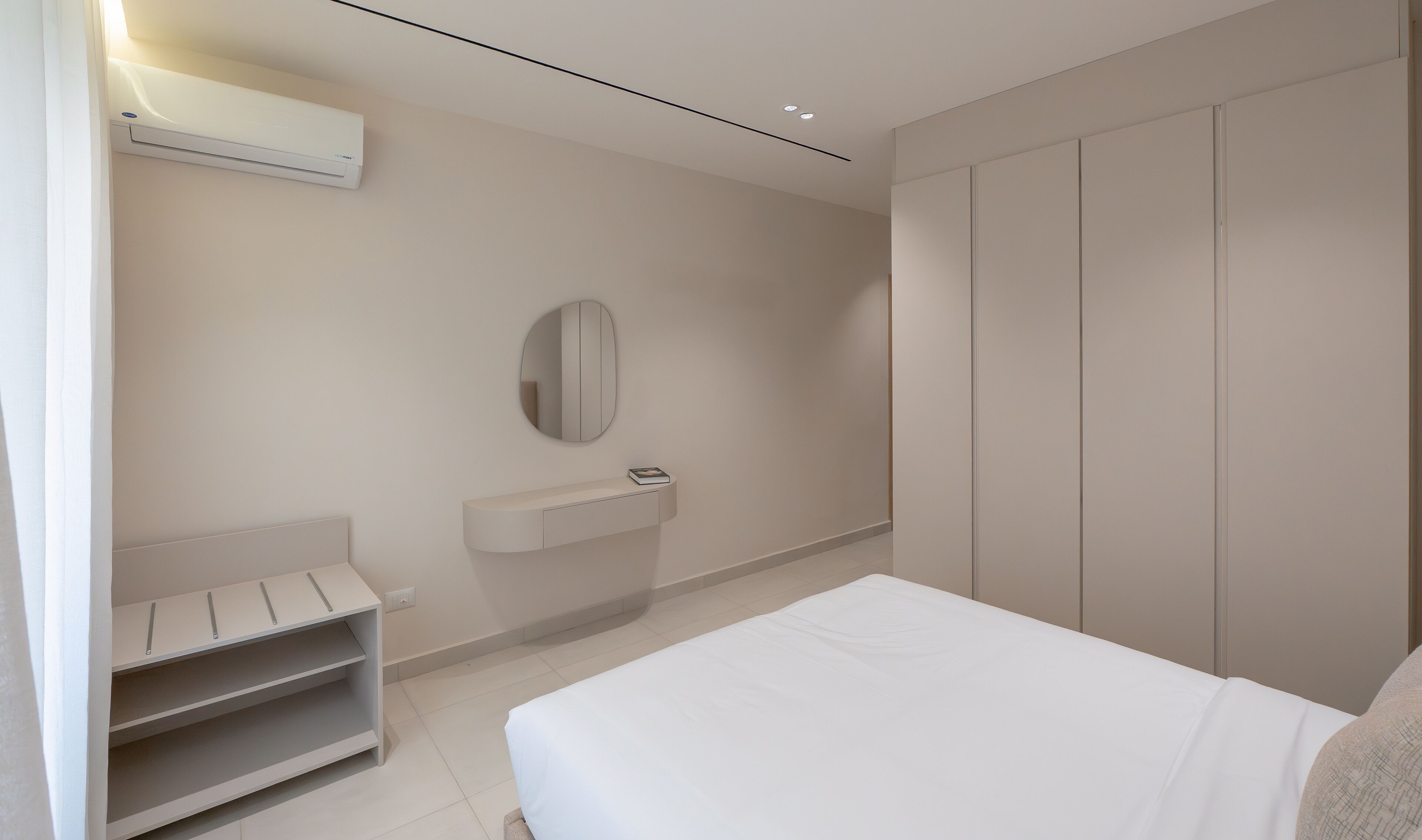 A modern bedroom with a bed, a vanity with a mirror, and a wardrobe.