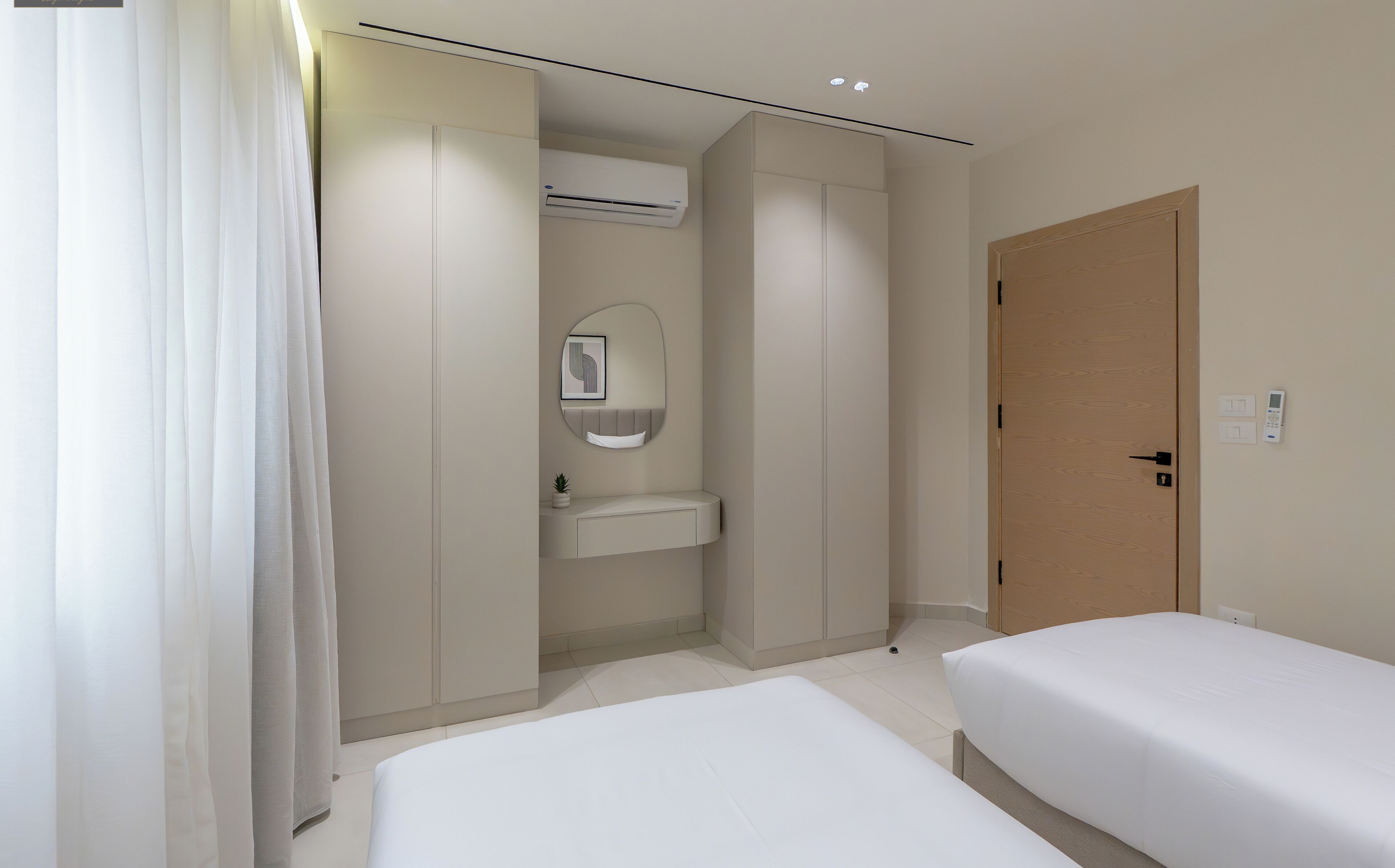 Ein modernes Hotelzimmer mit einem großen Bett, einem Nachttisch, einem Einbauschrank, einem kleinen Waschbecken und einem Spiegel.