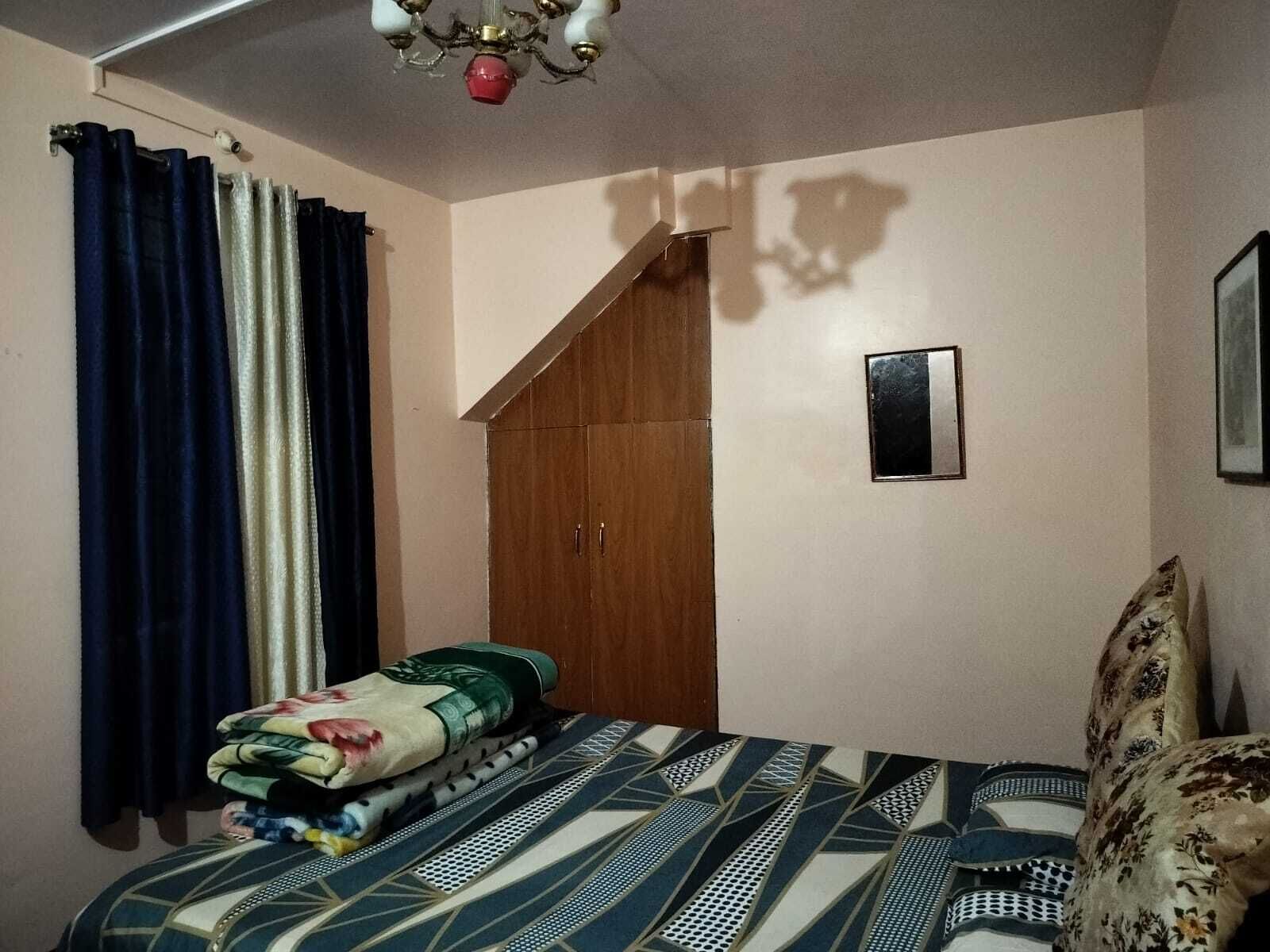 A bedroom with a bed, a wardrobe, a small framed picture, and a chandelier.