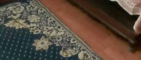 Un dormitorio con dos camas, un tapete estampado y un jarrón con flores.