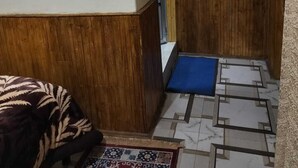 A hallway with a patterned rug, wooden paneling, and a framed picture on the wall. - benus (Darjeeling)