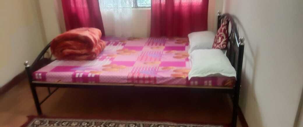 A single bed with a patterned bedspread, a pillow, and a blanket.