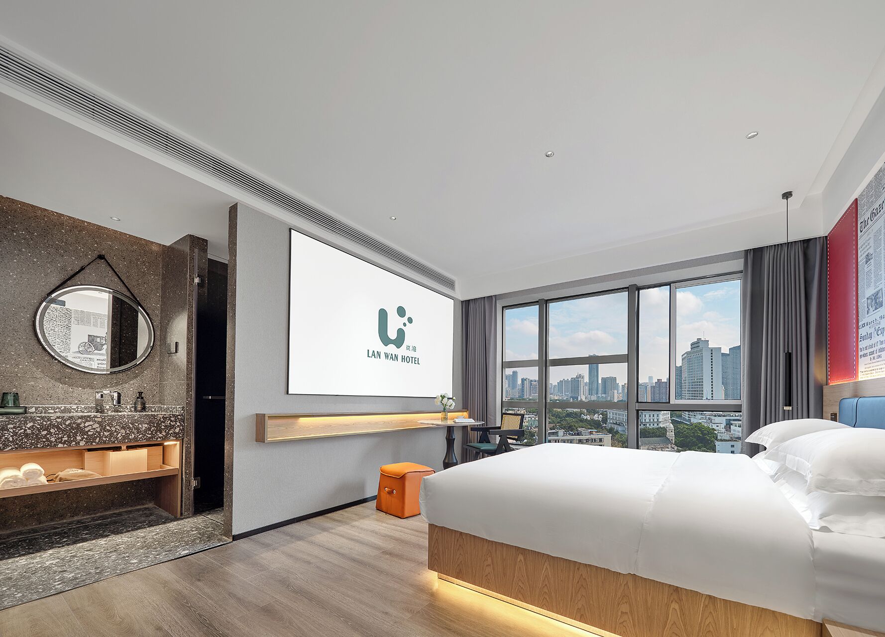 A modern hotel room with a large bed, a city view, a mounted TV, and a bathroom with a granite countertop.