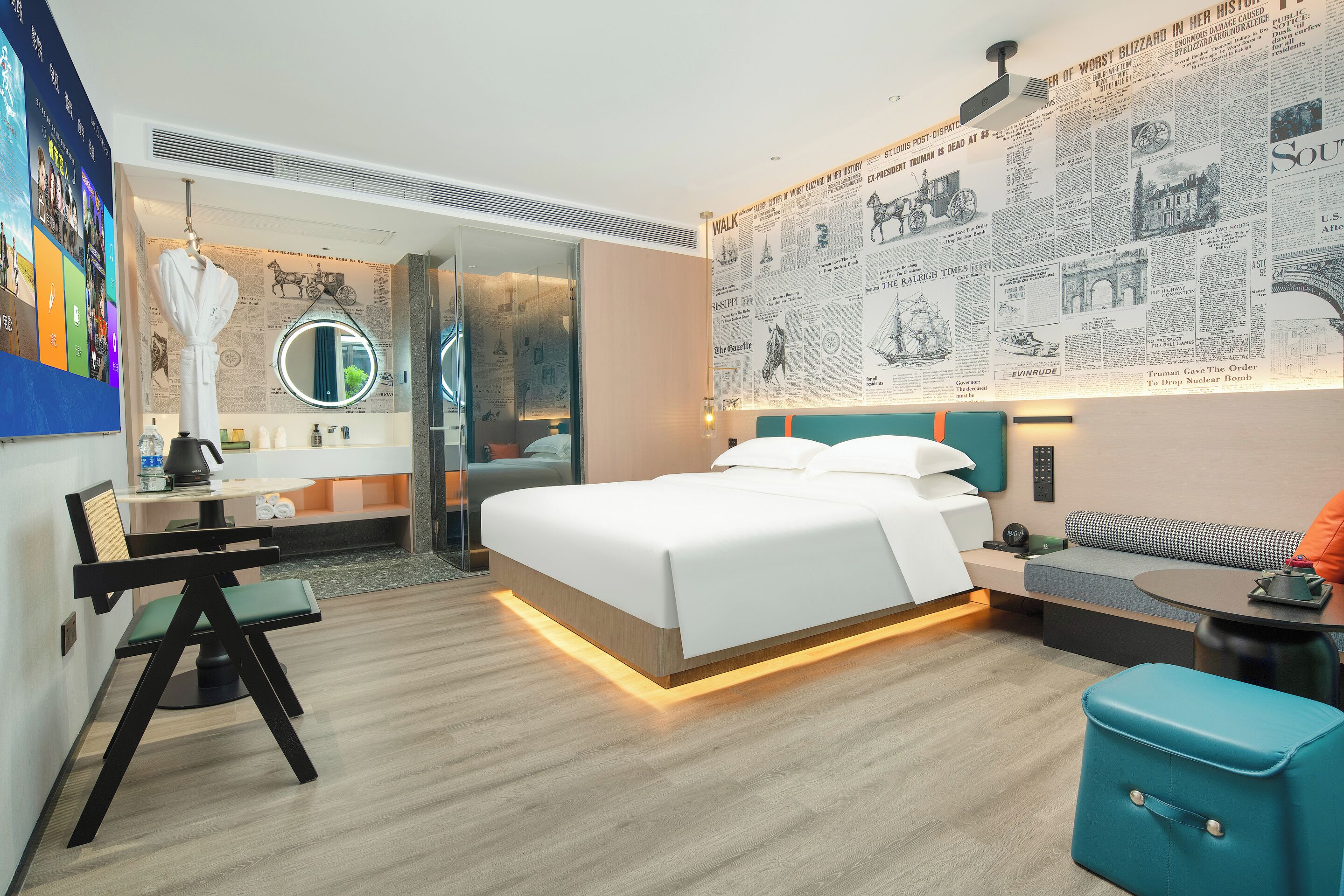 A modern hotel room with a large bed, a desk, a chair, a sofa, and a small table.