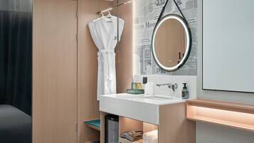 Un bagno moderno con un mobile bagno in legno, uno specchio rotondo e un accappatoio su un appendiabiti.