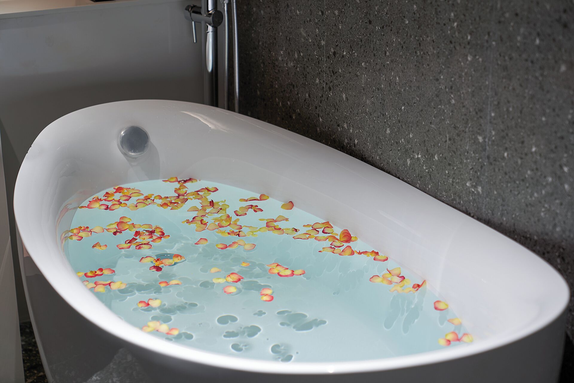 A bathtub filled with water and rose petals.