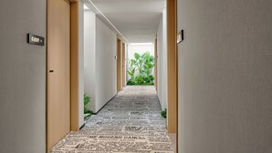 A hotel hallway with a carpet featuring newspaper clippings, wooden doors, and a view of greenery at the end. - Lan Wan International Hotel  (Guangzhou)