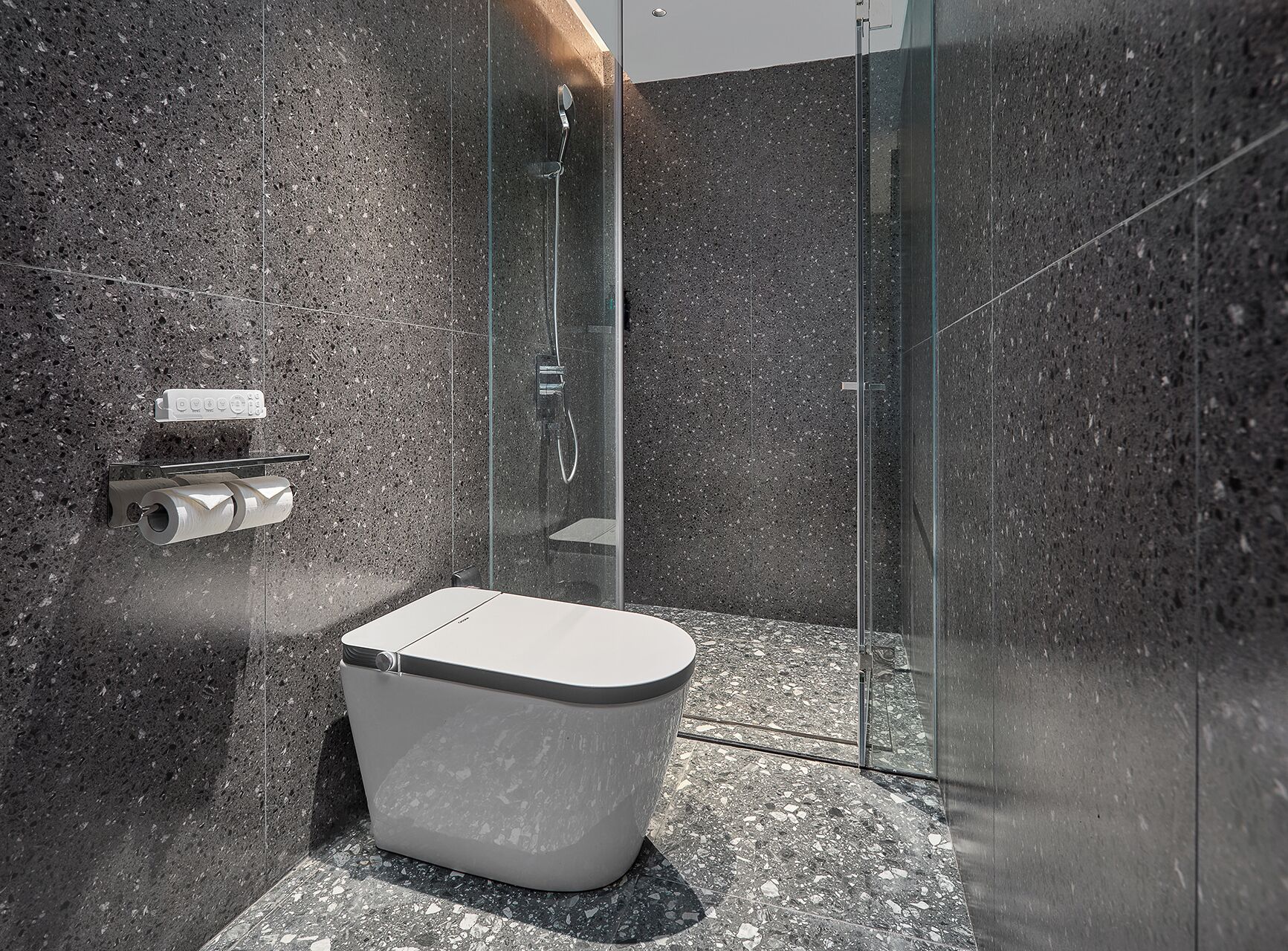A modern bathroom with a glass-enclosed shower, a white toilet, and a marble floor.