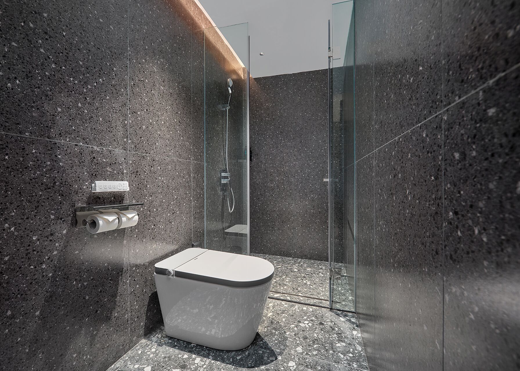 A modern bathroom with a glass-enclosed shower, a toilet, and a marble-tiled wall.