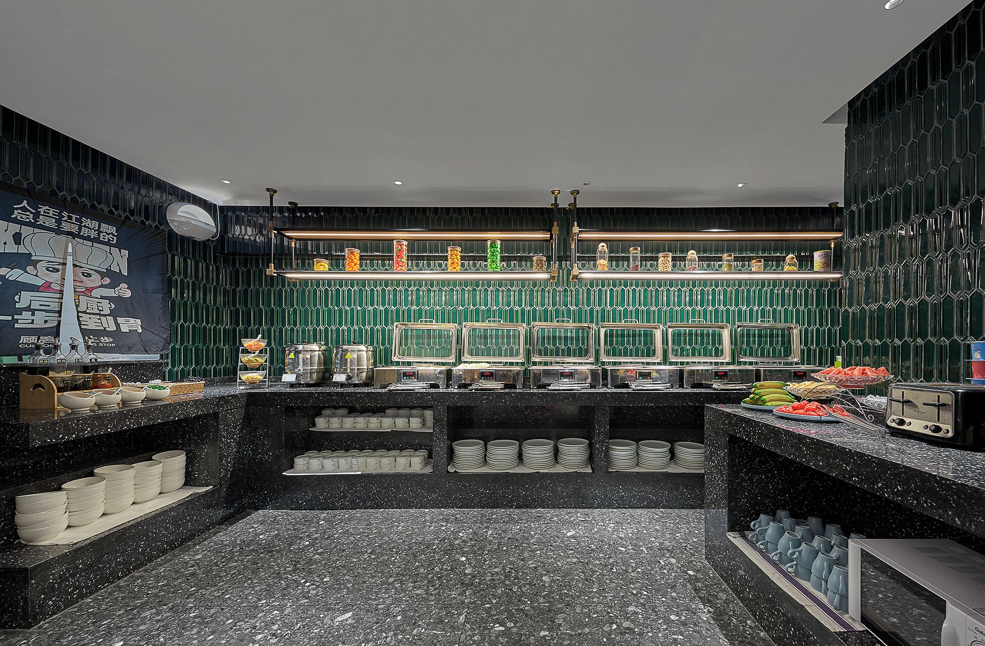 Una cocina moderna con encimera de mármol negro, salpicadero de azulejos verdes y varios electrodomésticos.