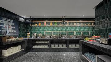 Una cocina moderna con encimera de mármol negro, salpicadero de azulejos verdes y varios electrodomésticos.