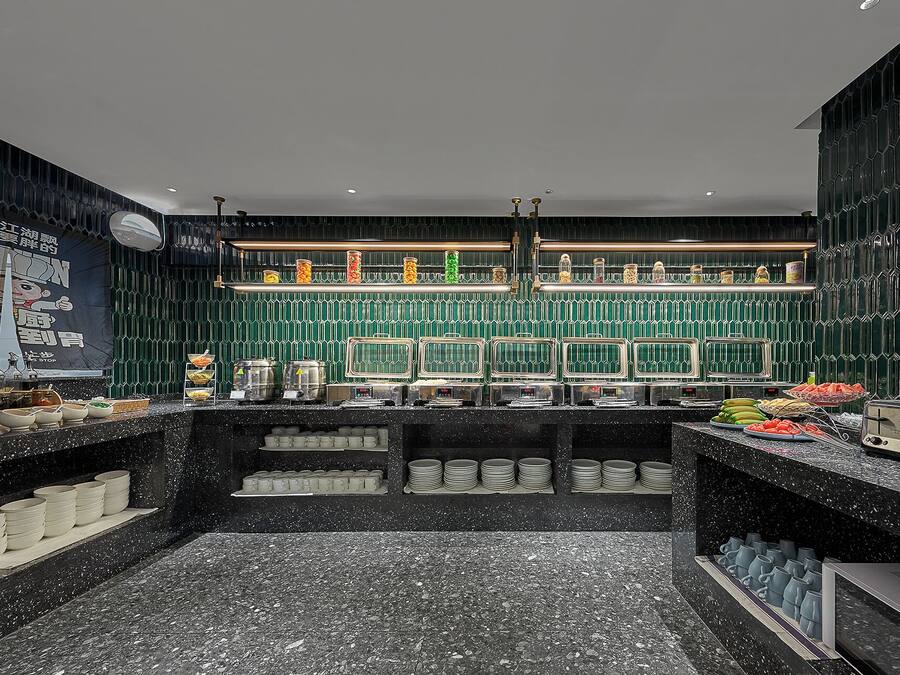 Una cocina moderna con encimera de mármol negro, salpicadero de azulejos verdes y varios electrodomésticos.
