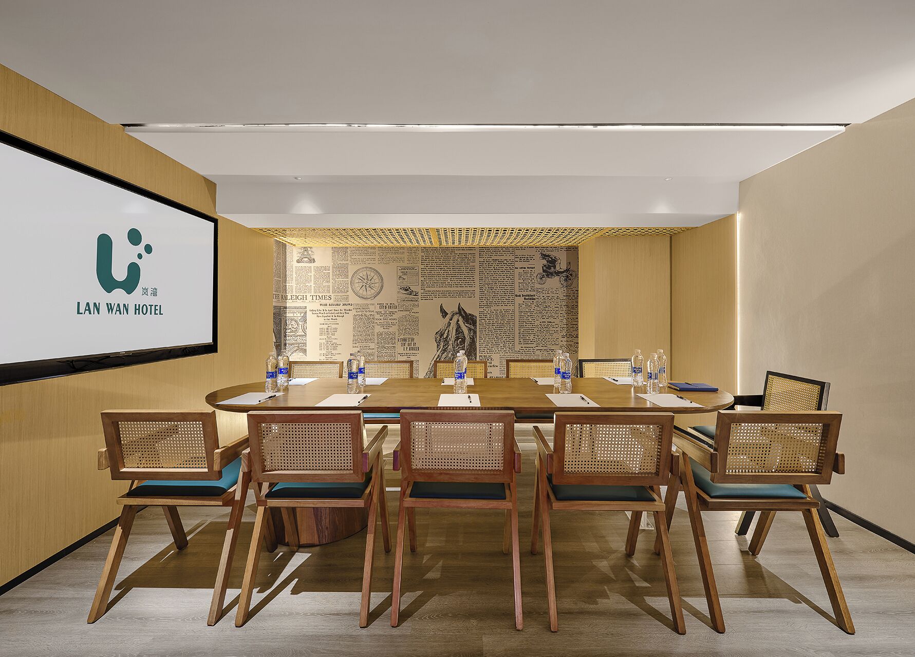 A conference room with a long table, six chairs, and a screen displaying the Lan Wan Hotel logo.