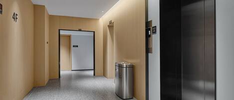 A modern hallway with a trash bin, an elevator, and a door marked "4F".