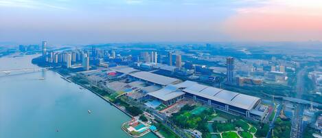 An aerial view of a cityscape with a river, high-rise buildings, and a large stadium.